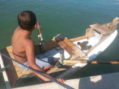 Un'altra inquadratura del ragazzino e del suo piccolo capolavoro di ingegneria nautica